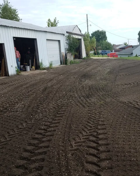 Compacted millings yard in front of a farm machine shed